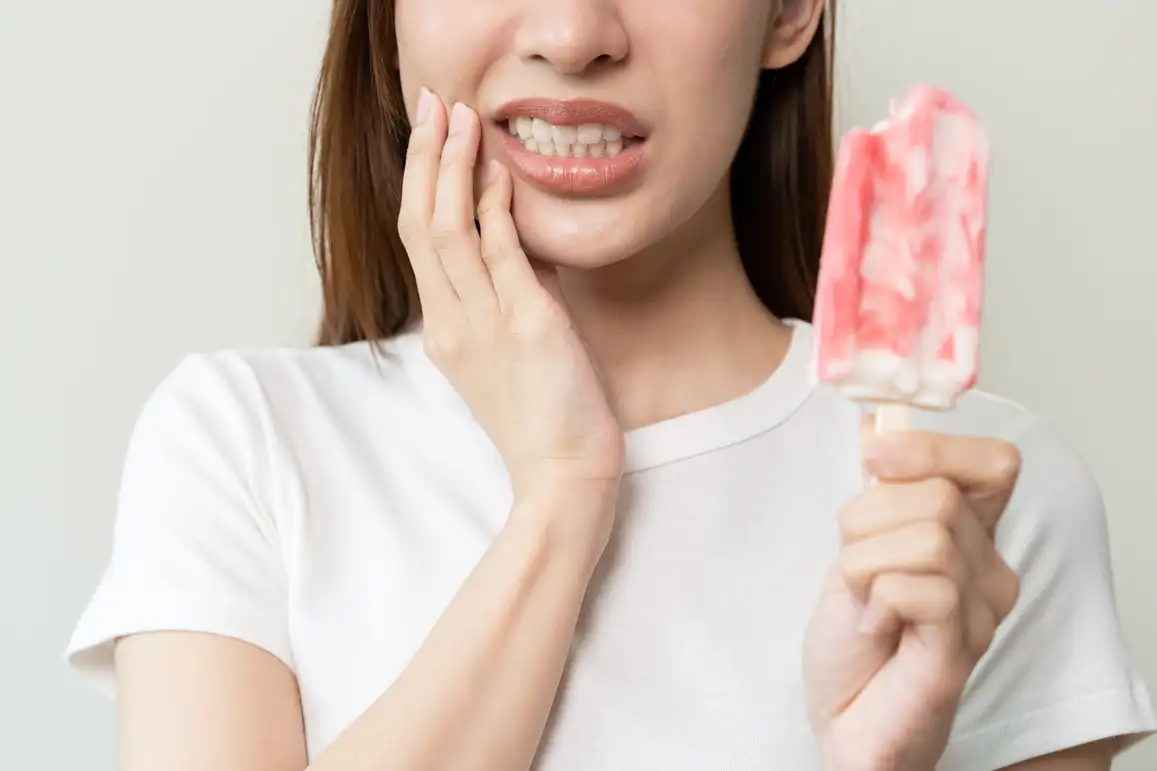 Woman needing tooth sensitivity relief from cold - why are my teeth sensitive